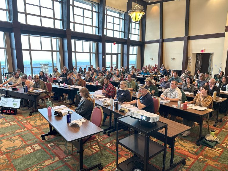 A room full of people seated at tables attending a Training Conference.