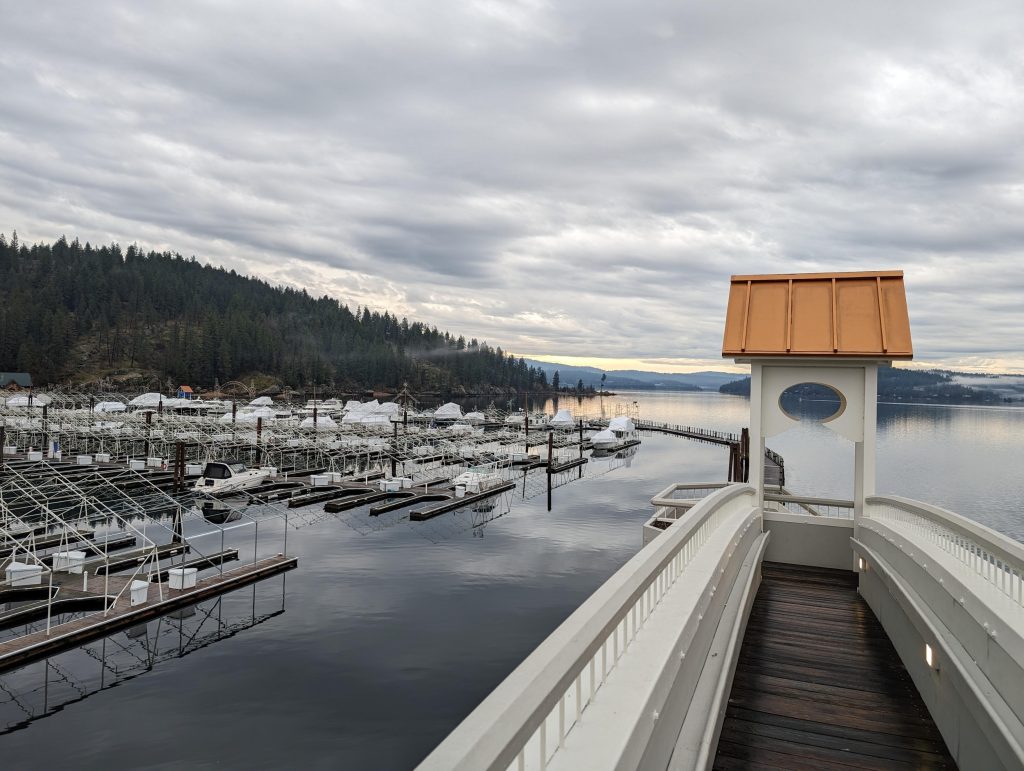 Image of a marina with boats in the foreground and mountain in background.