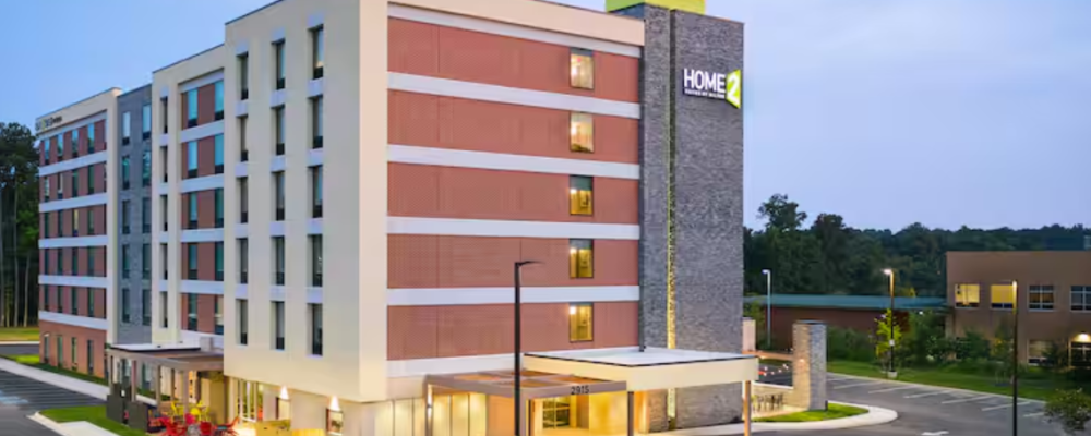 Image of multiple story hotel with covered entrance and parking area